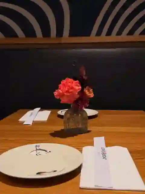 A table set with flowers and branded chopstick sleeves at Love Boat Sushi.